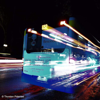 Bus mit Wollenhaupt Werbung bei Nacht mit Lichtstreifen