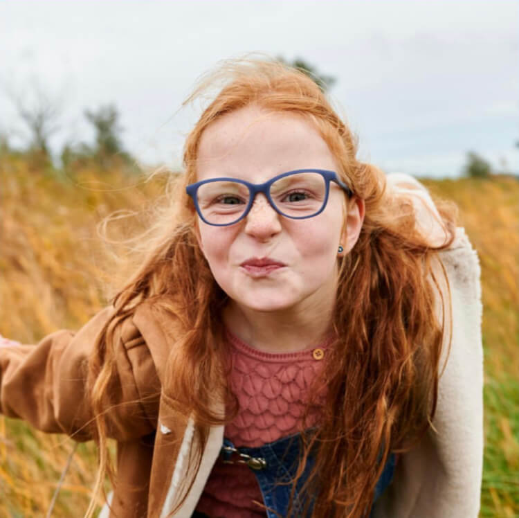 Lustiges Mädchen mit roten Haaren trägt Brille